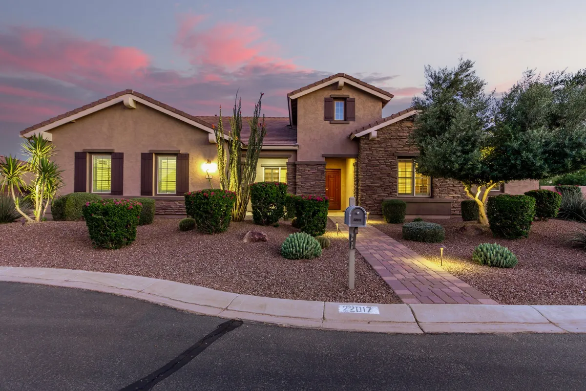 A welcoming exterior view of the home features a beautifully landscaped front yard, a well-lit entryway, and inviting front door. The setting is perfect for gatherings, with ample space for relaxing outdoors and enjoying the sunset.
