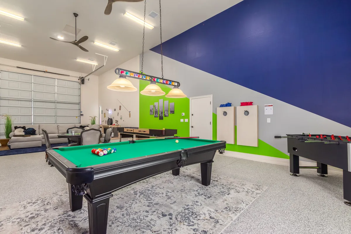 This image showcases a vibrant game room with a pool table, foosball table, brightly painted walls, and comfortable seating. The space exudes energy and invites guests to engage in playful competition and socializing.