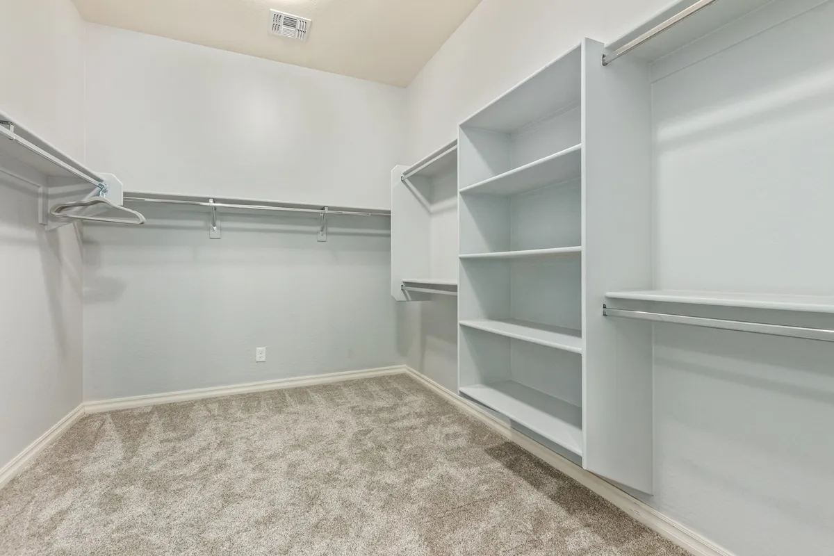 A well-organized walk-in closet with shelves, hanging rods, and soft carpeting—ideal for storing clothes and personal belongings, contributing to a clutter-free and extended-stay experience.
