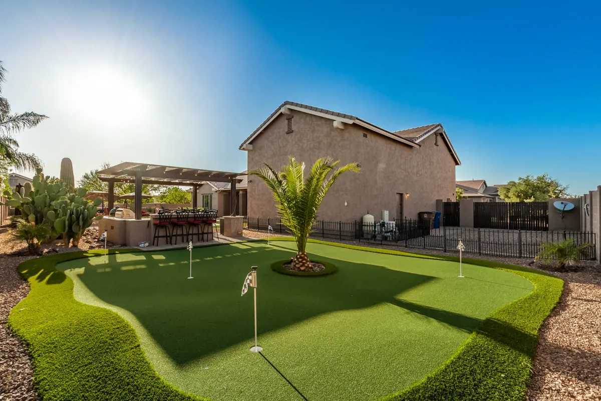 A lush putting green with a palm tree and an adjacent outdoor seating area, capturing the spirit of outdoor leisure and community. The scene hints at fun golf games and casual gatherings with friends or family against a backdrop of Arizona sunshine.