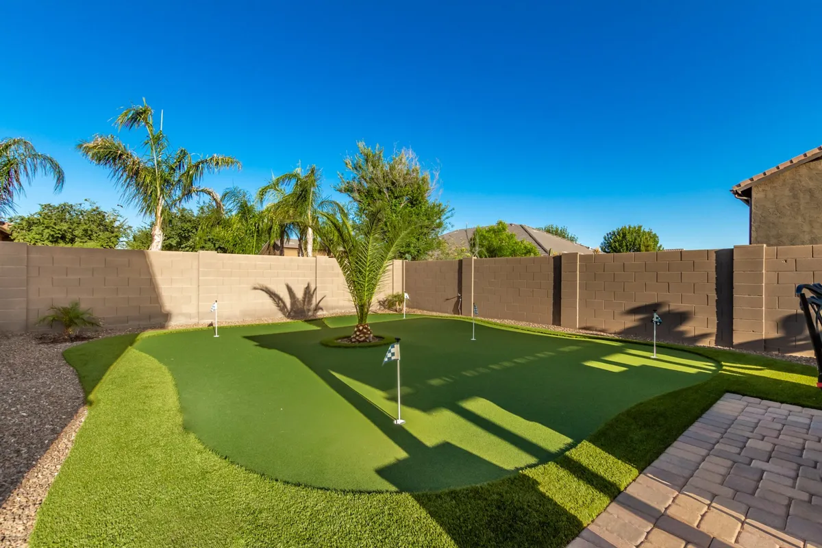A synthetic putting green framed by palm trees and privacy walls, evoking a playful, active, and relaxed outdoor experience for golf enthusiasts and casual fun alike.