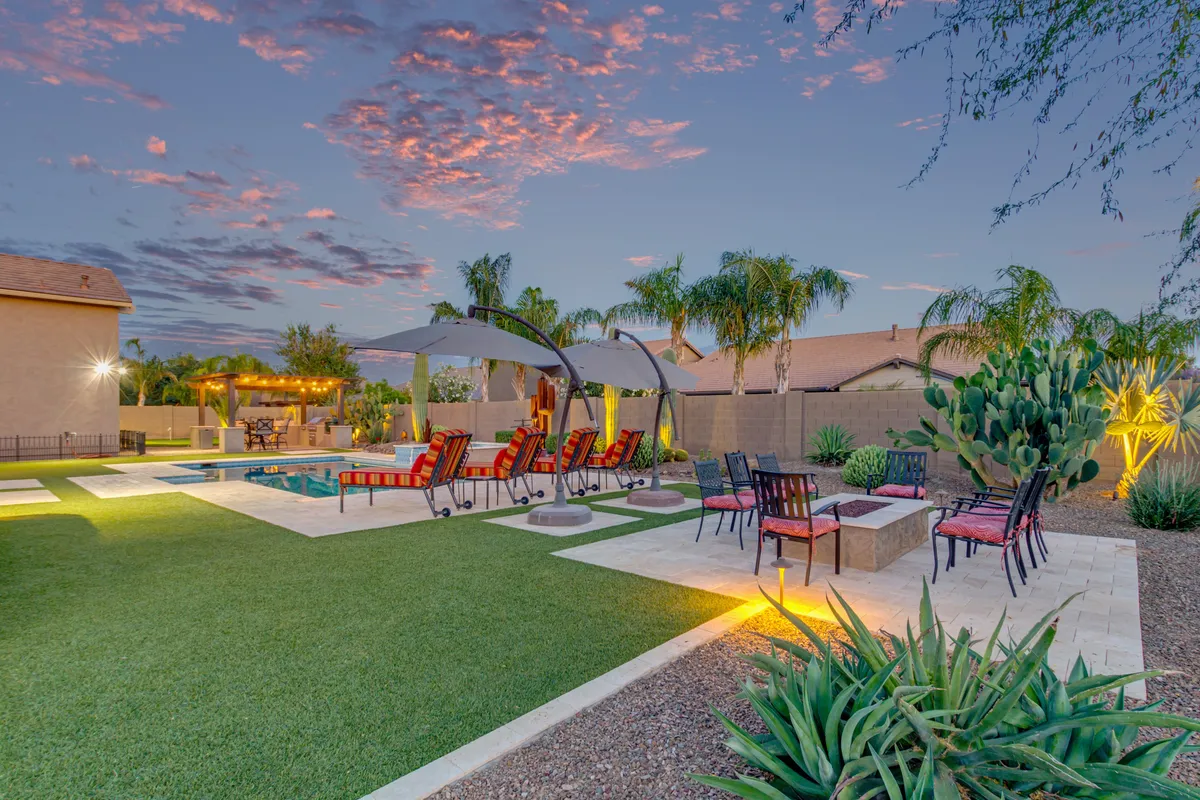 An expansive backyard scene featuring a sparkling swimming pool, luxury lounge chairs, a cozy fire pit, and lush landscaping creates a tranquil and inviting atmosphere for both relaxation and entertaining.